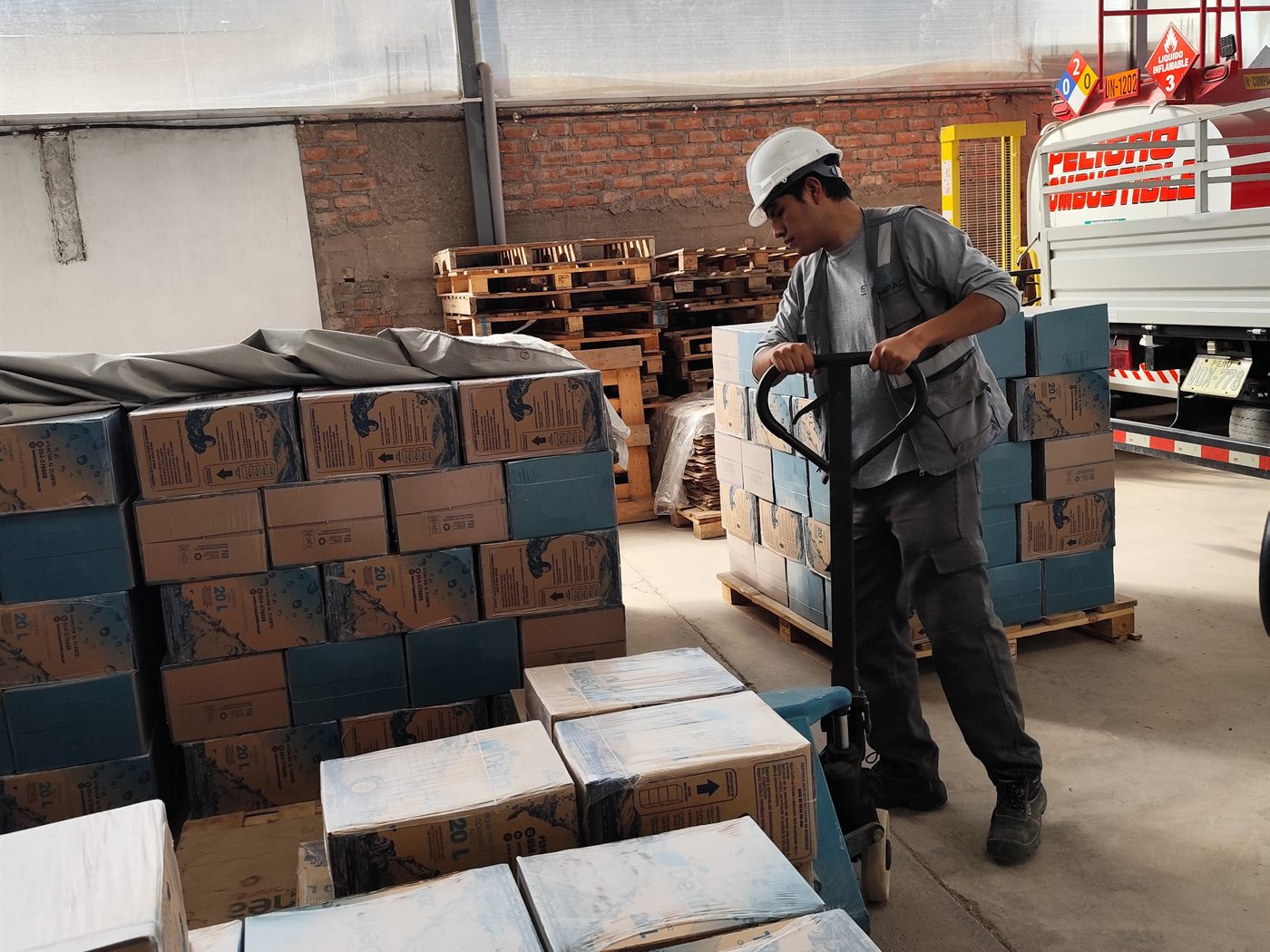 Operario de EMPAC trasladando un pallet con cajas de agua Delfín hacia el camión de reparto